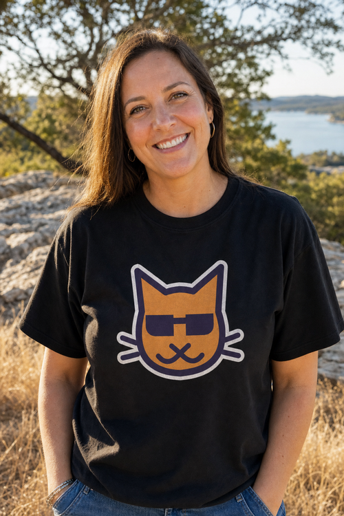 Blind Kitty Tee in Black on a woman above Lake Travis, the big Blind Kitty on the front (AI-generated scene)