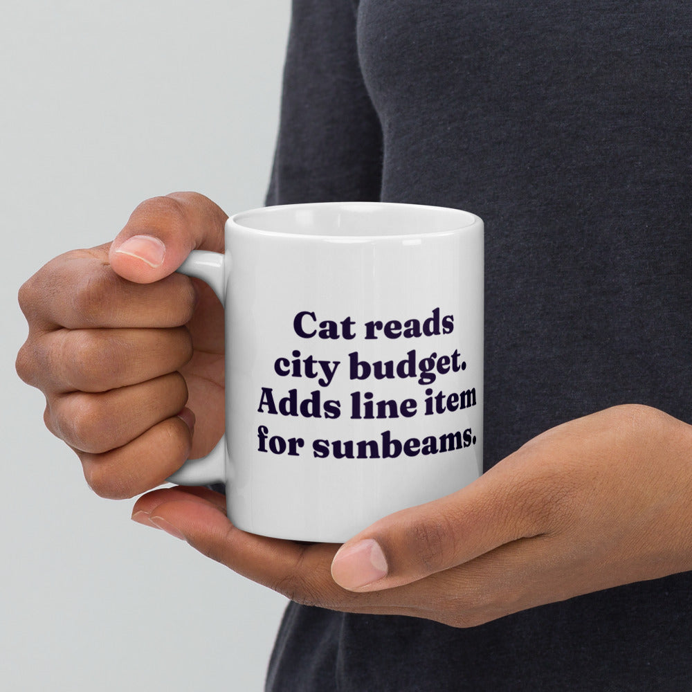 Sunbeams Line Item mug held in two hands: Cat reads city budget. Adds line item for sunbeams.